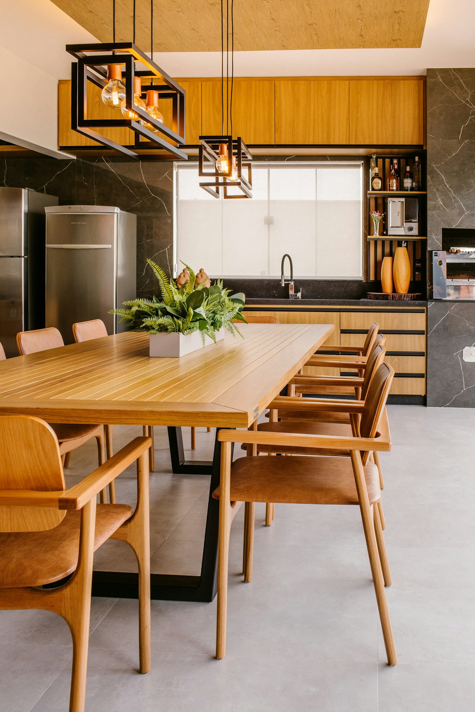 Warm timber kitchen opening onto a dining table with pendant lights
