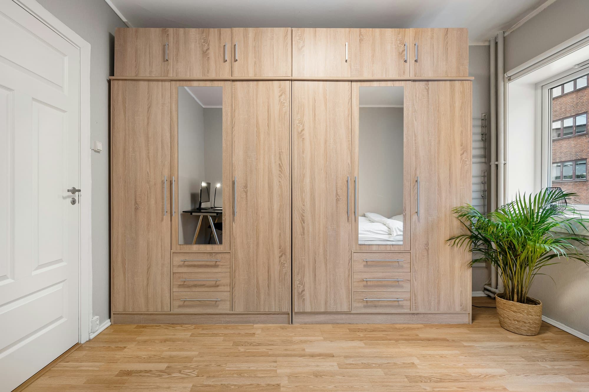 Full-height oak wardrobe with mirrored doors in a bright bedroom
